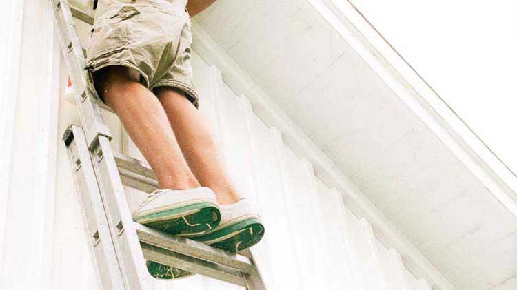 A man cleaning gutters on the roof of a house.