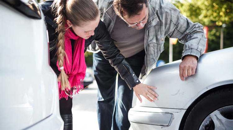 People looking at scratches on a car resulting from a car accident.